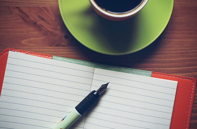 ノートに万年筆で記録をつける様子とコーヒー